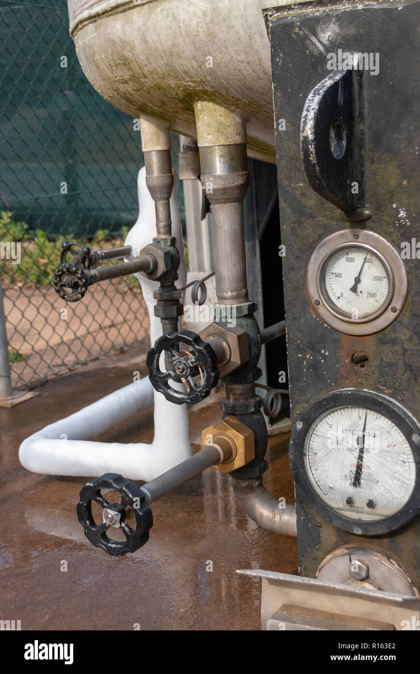 The bottom view of a liquid oxygen tank with the pressue gauges in the front and some of the liqud has leaked and solidified into ice over the pipes Stock Photo