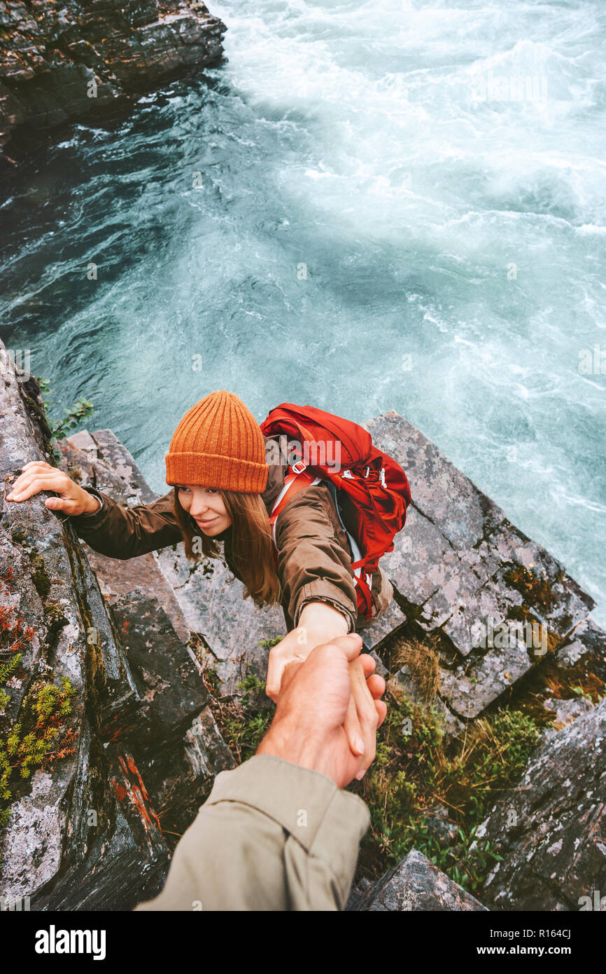 Travel couple helping hand holding together on rocks over river man and woman family adventure lifestyle vacations outdoor exploring wilderness Stock Photo