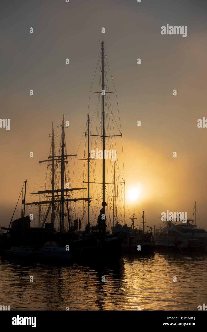 Ships silhouetted against dawn sky in Poole Stock Photo
