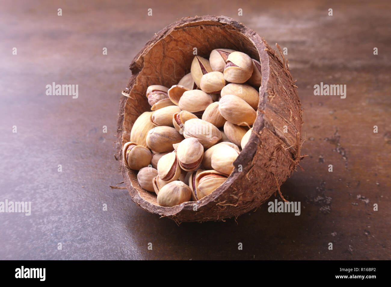 handmade bowl of coconut with pistachios on a stone table. Close-up. Stock Photo