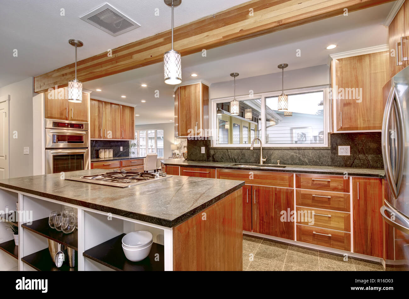 Luxurious kitchen room with stainless steel appliances, dark counter tops and tiled floor. Stock Photo