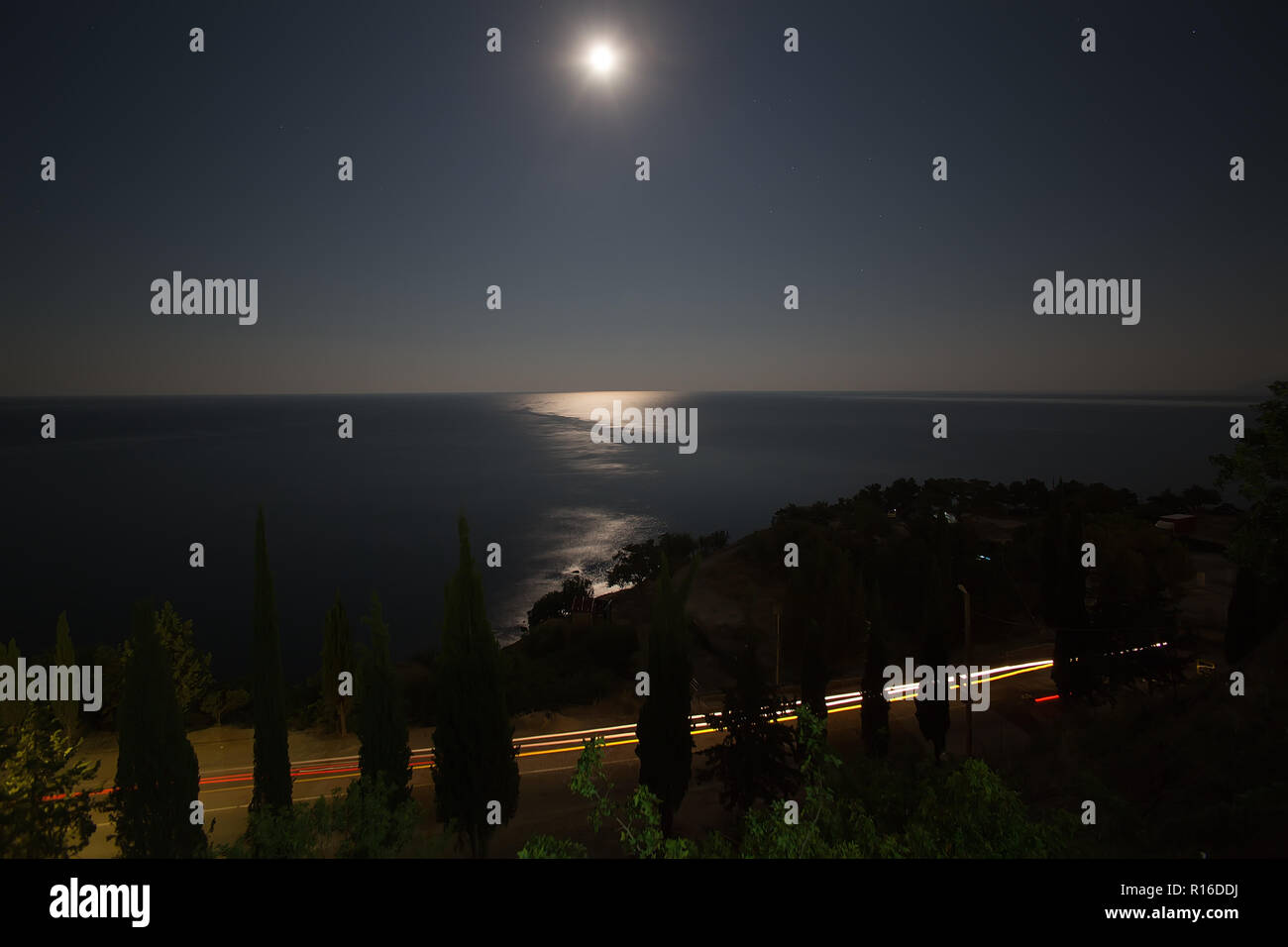 Seashore highway, horizon sky and moon at night Stock Photo