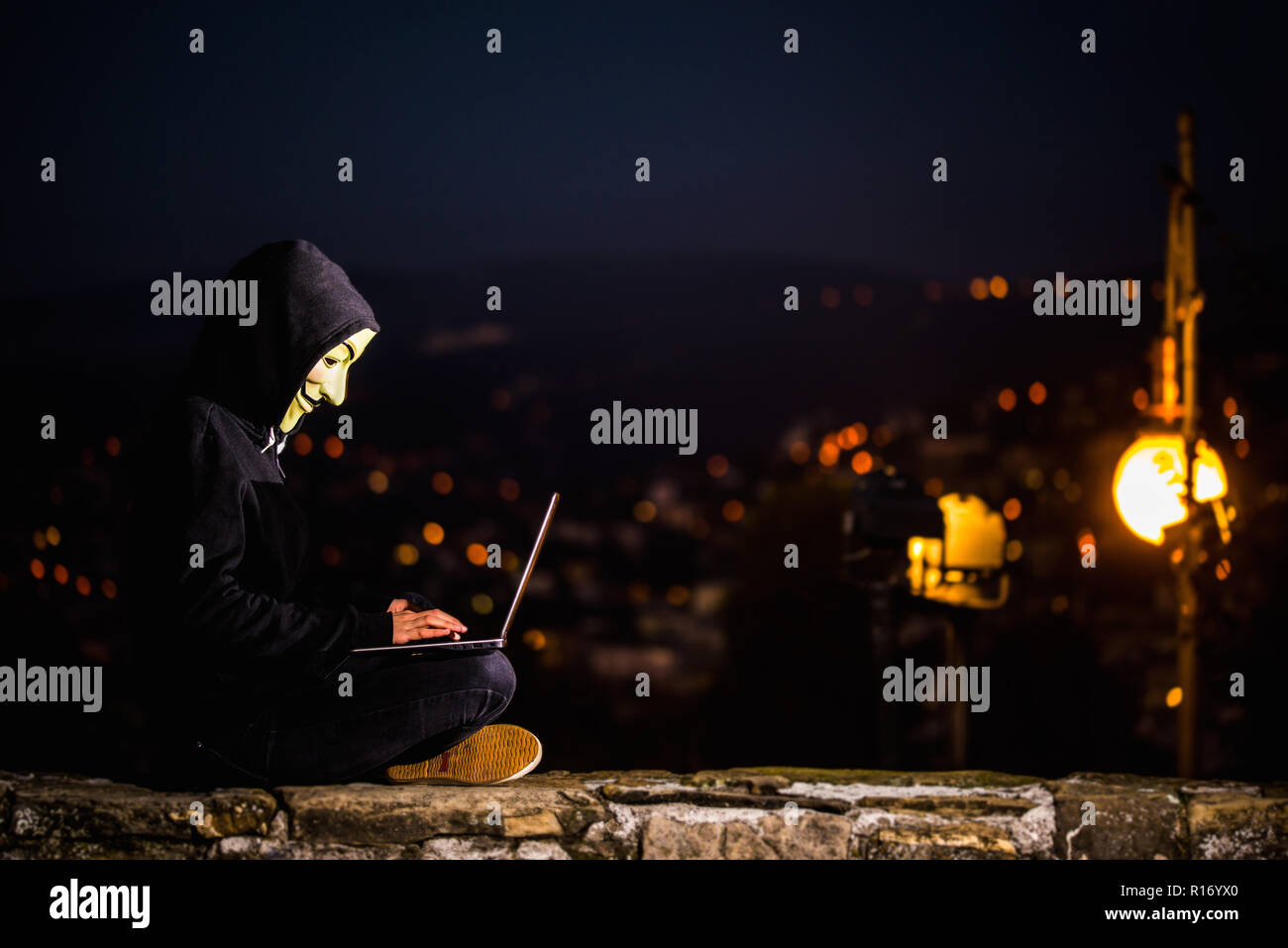 Trieste, Italy, 08 november 2018. An indifinited person with Anonimus mask and notebook in the night street. Concept of informatic security Stock Photo