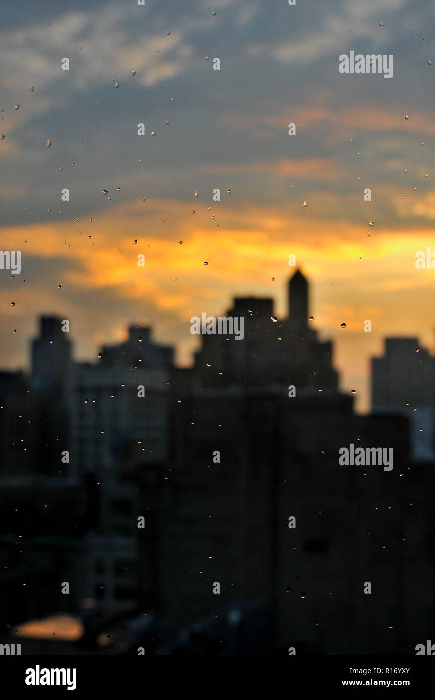 Rain drops on the window with unfocus view to Manhattan skyline during sunset time. Stock Photo