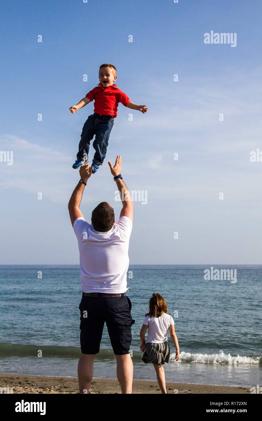 Father Plays with a happy son on the beach in Spain Stock Photo