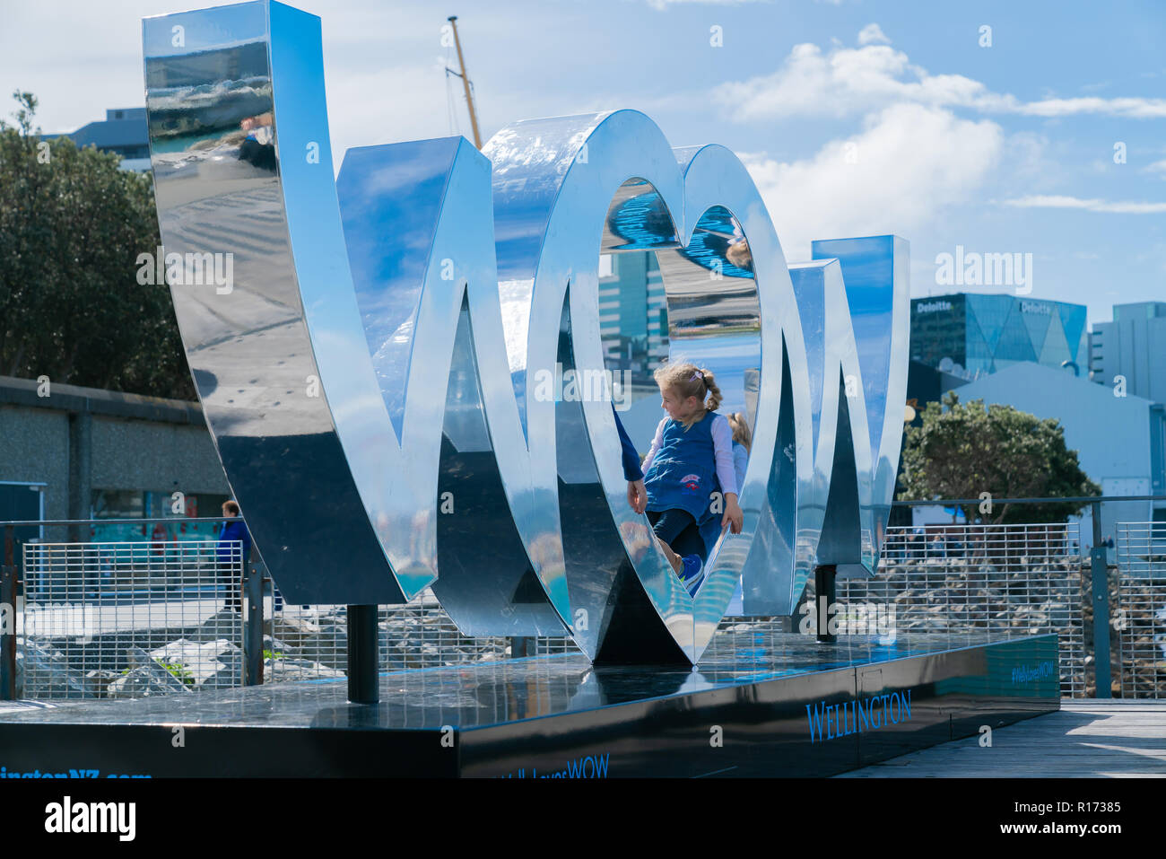 WELLINGTON, NEW ZEALAND - OCTOBER 1 Child plays in centre heart shaped O in World of Wearable Art iconic shiny silver sign on city waterfront reflects Stock Photo