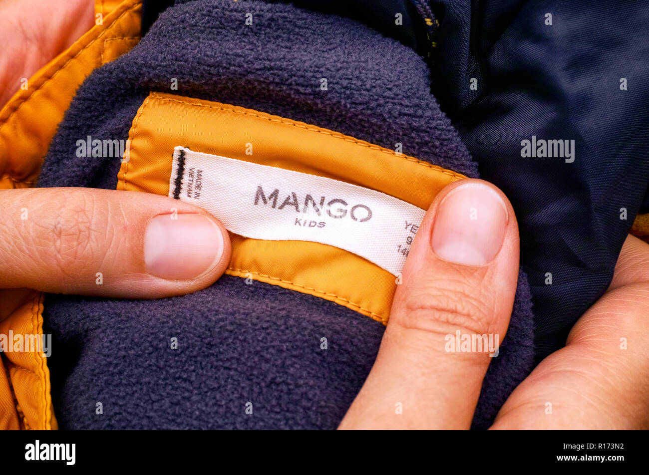 Russian Federation - 2018 Woman hands holding yellow jacket with Mango Kids clothes label. Close-up Stock Photo - Alamy