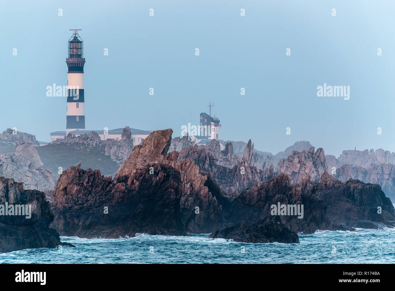 Sharp rocky coastline and Creach lighthouse in the Ushant island, Brittany, France Stock Photo