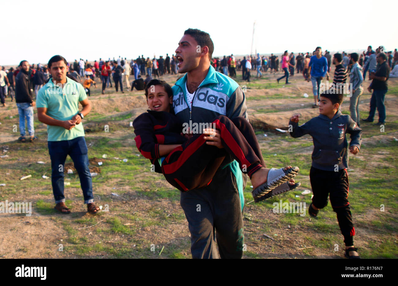 Palestinian man seen carrying an injured child during the protest. Demonstration between the Israeli soldiers and Palestinian citizens during a protest against the decision of President Trump to recognise Jerusalem as the capital of Israel and rejects the Israeli siege at the Gaza Strip. Stock Photo
