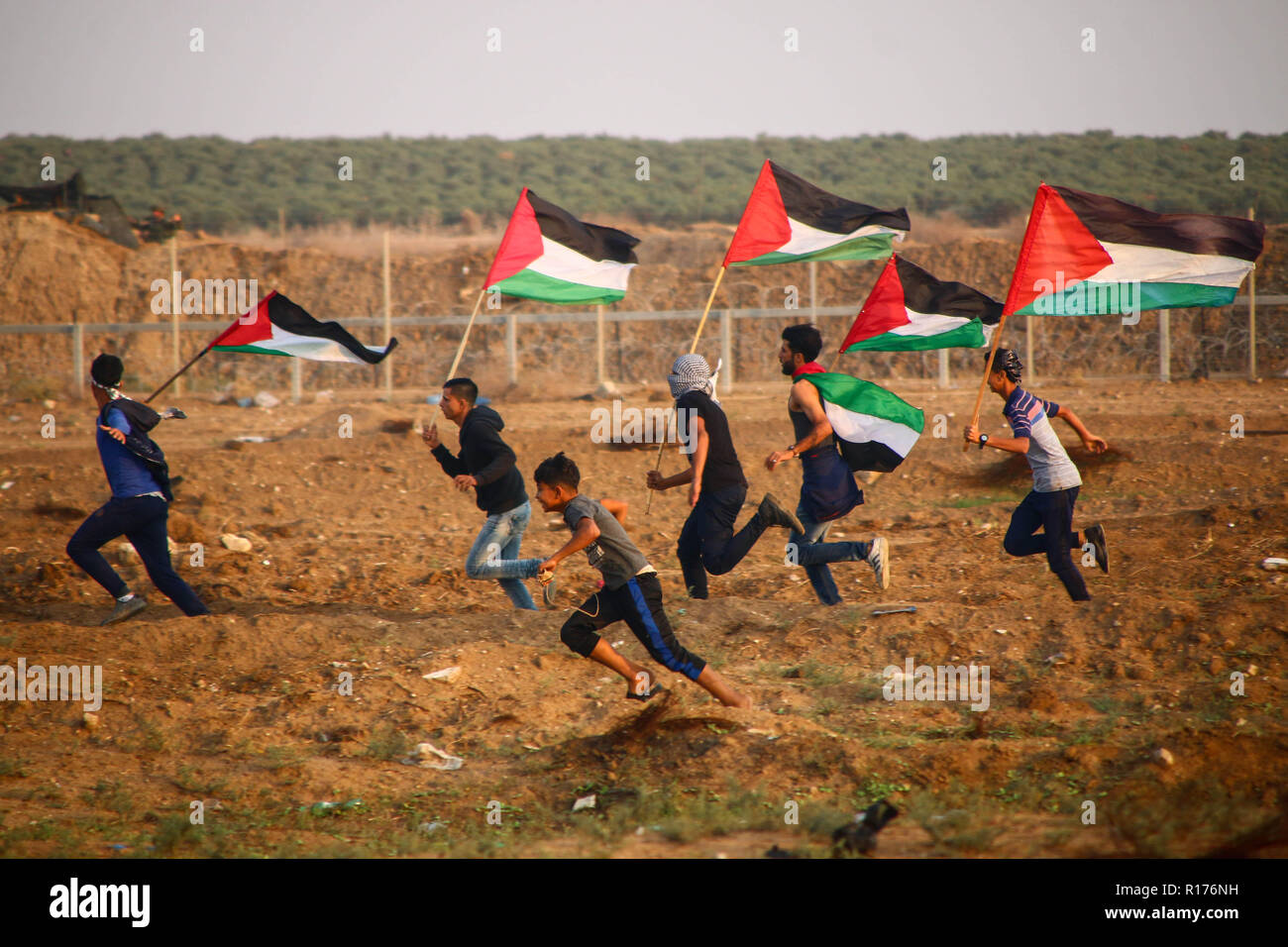 Palestinian youth are seen flying Palestine flags during the protest. Demonstration between the Israeli soldiers and Palestinian citizens during a protest against the decision of President Trump to recognise Jerusalem as the capital of Israel and rejects the Israeli siege at the Gaza Strip. Stock Photo