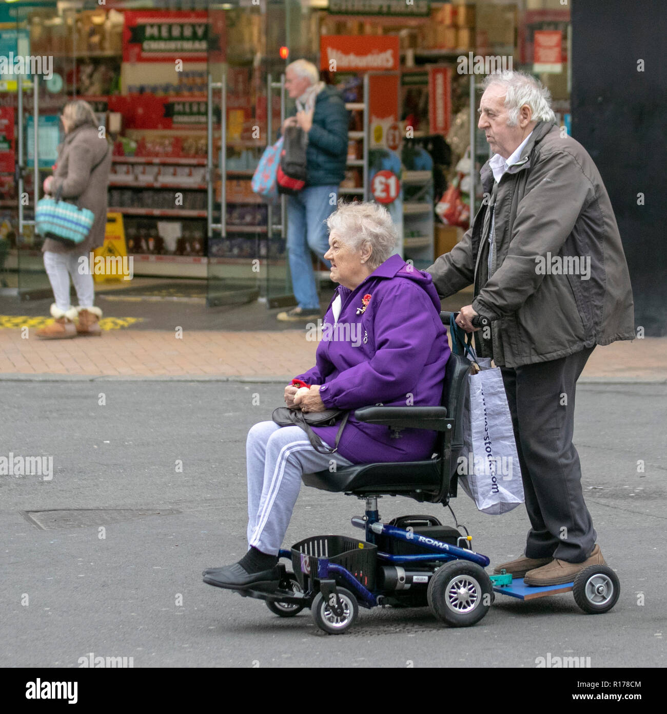 Elderly couple, on Modified battery powered mobility scooter adapted with a trailer carrying two people in Blackpool, UK Stock Photo