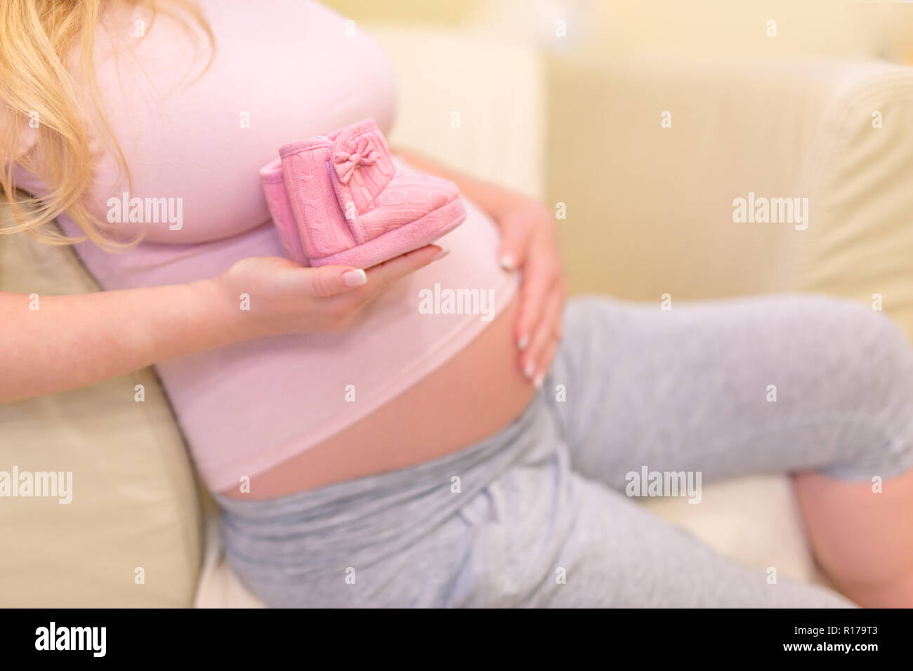 Small shoes for the unborn baby in the belly of pregnant woman. Pregnancy concept Stock Photo