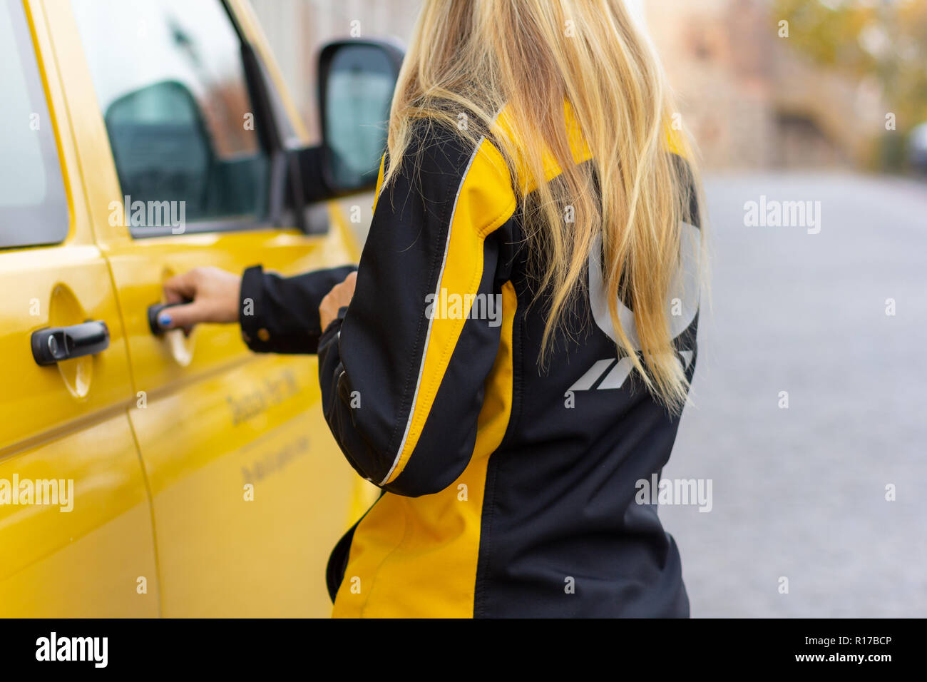 BERLIN / GERMANY - NOVEMBER 9,2018: Female postman from Deutsche Post and DHL on yellow postcar. Stock Photo