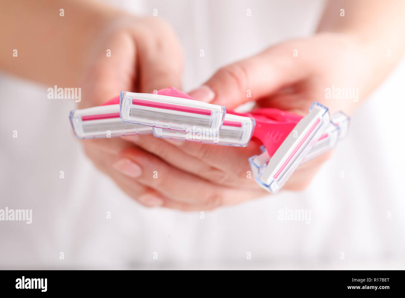 Disposable shaver in female hand on abstract blurred white background. Epilation, razor hair