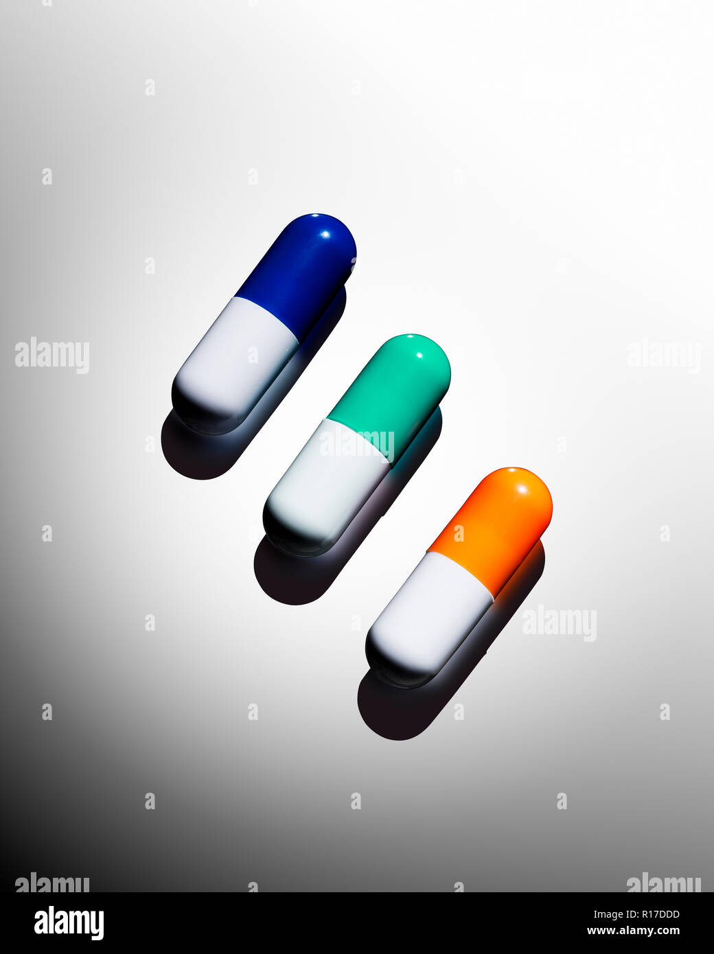 A row of three colourful medication pill capsules, still life Stock Photo