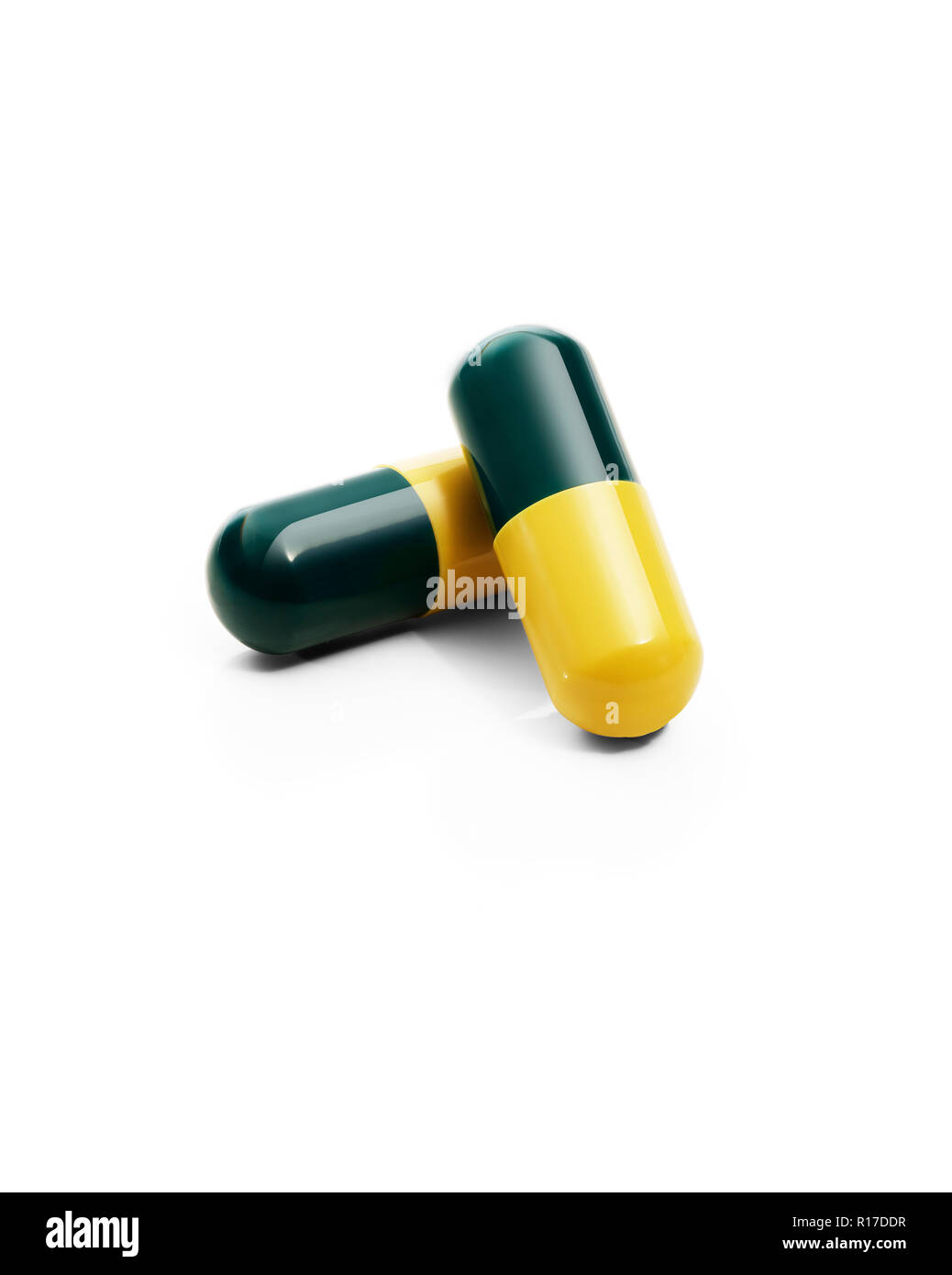 Two dark green and yellow medication pill capsules, still life Stock Photo