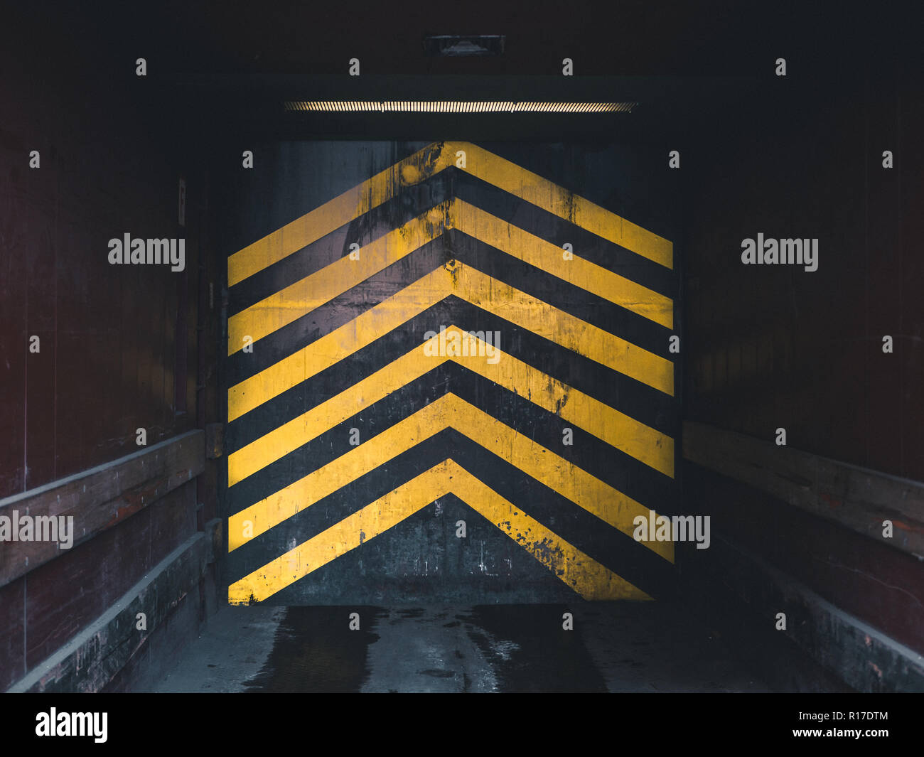 looking inside an industrial elevator in a factory, with yellow arrows pointing upwards Stock Photo