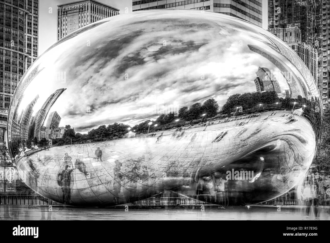 a public art piece stands amid tall buildings in Chicago along the lakefront in this long exposure showing the blur of people moving around it. Stock Photo