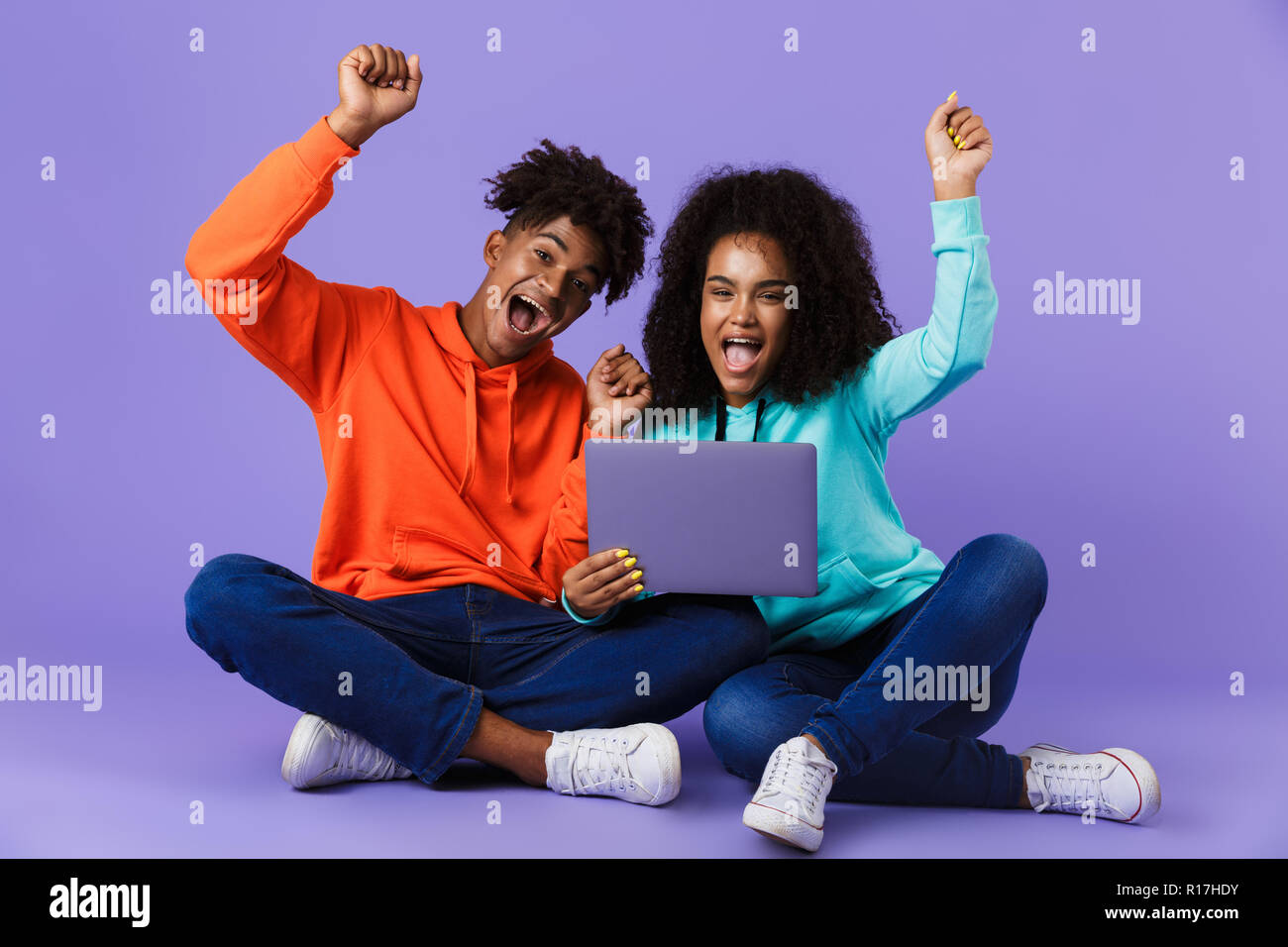 Image of happy young cute african couple sitting isolated over violet ...