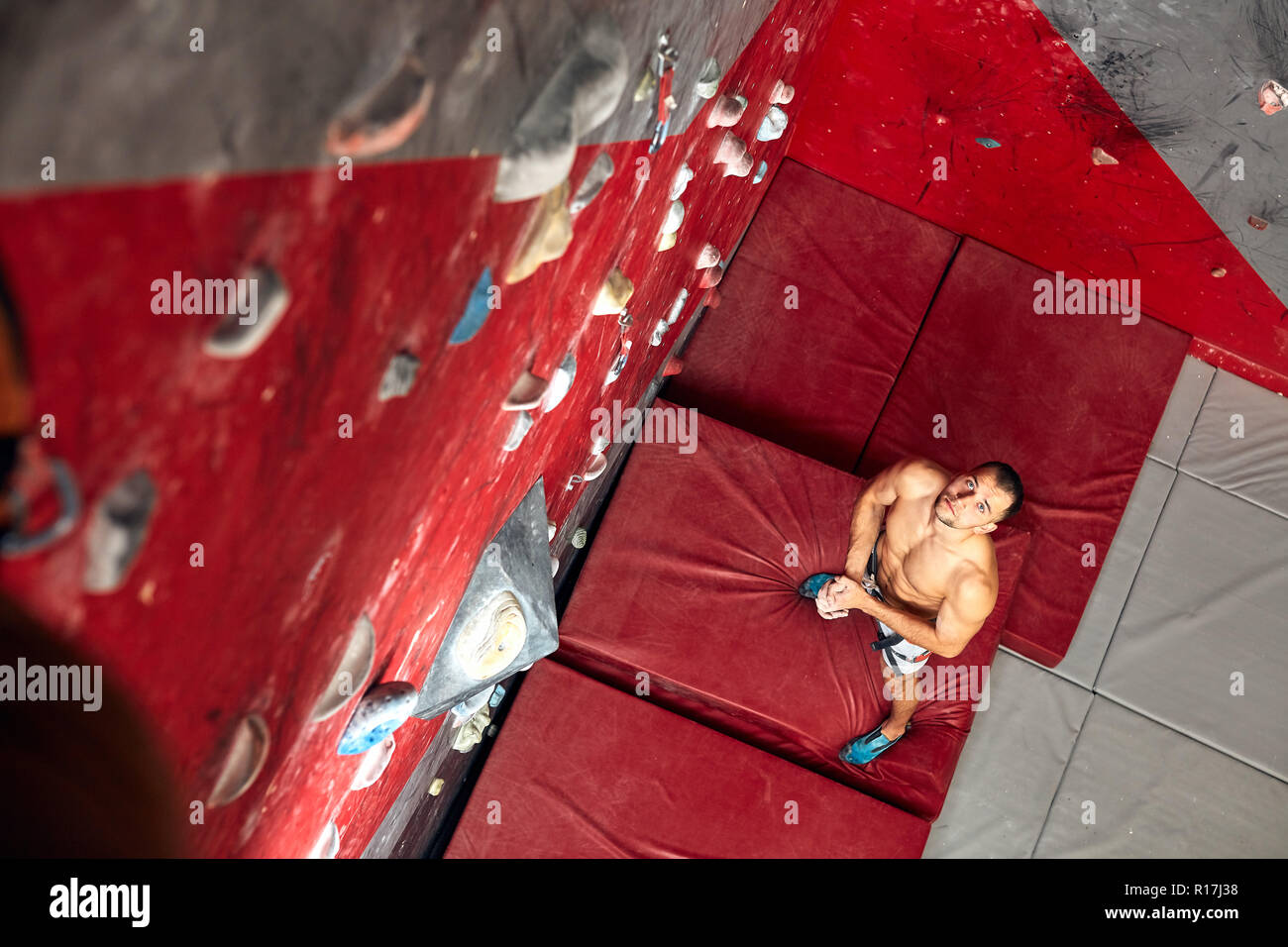 Panoramic man bouldering at an indoor climbing centre. Stock Photo