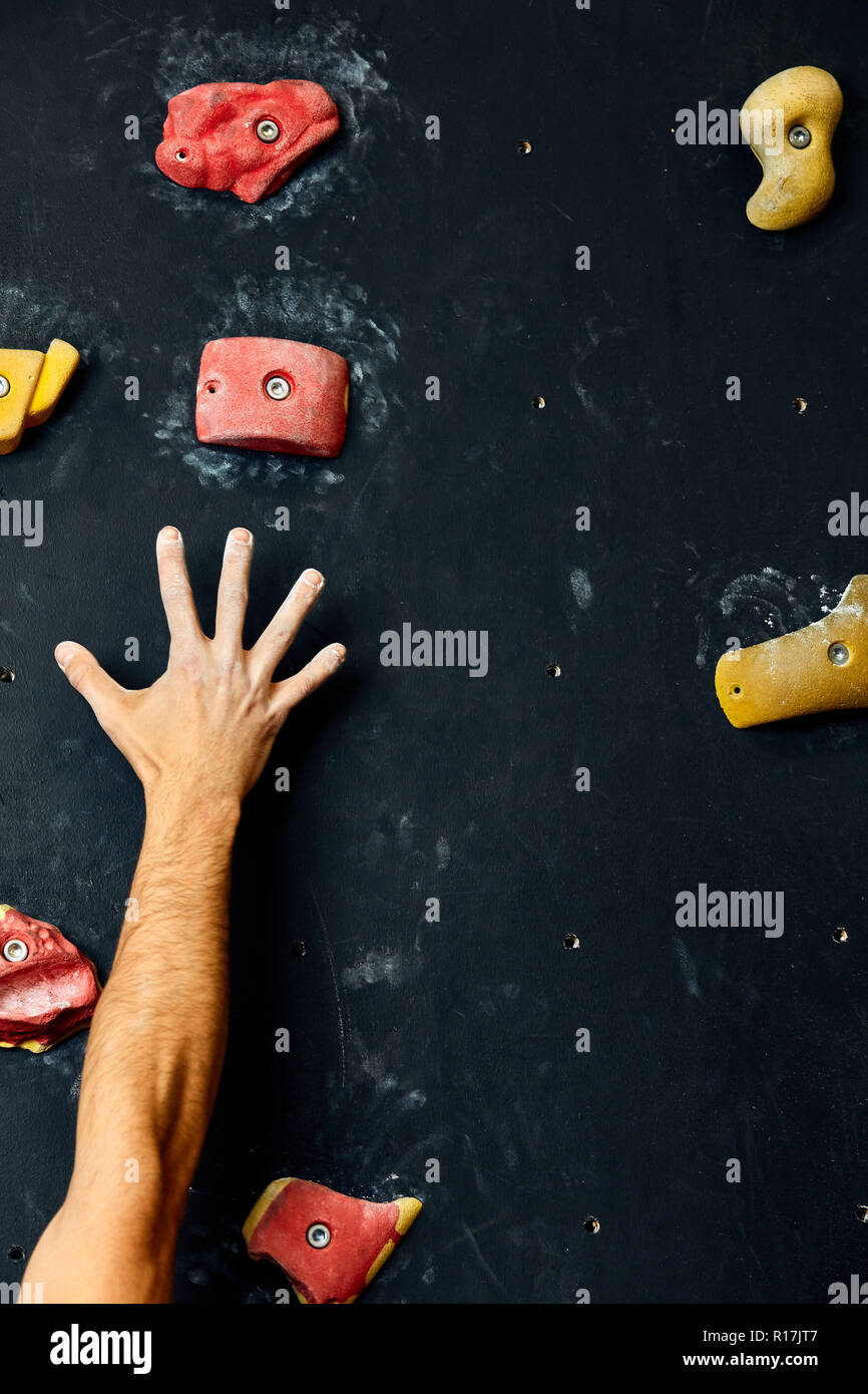 Macro shot of climbers hands gripping colourful handholds during indoor workout Stock Photo