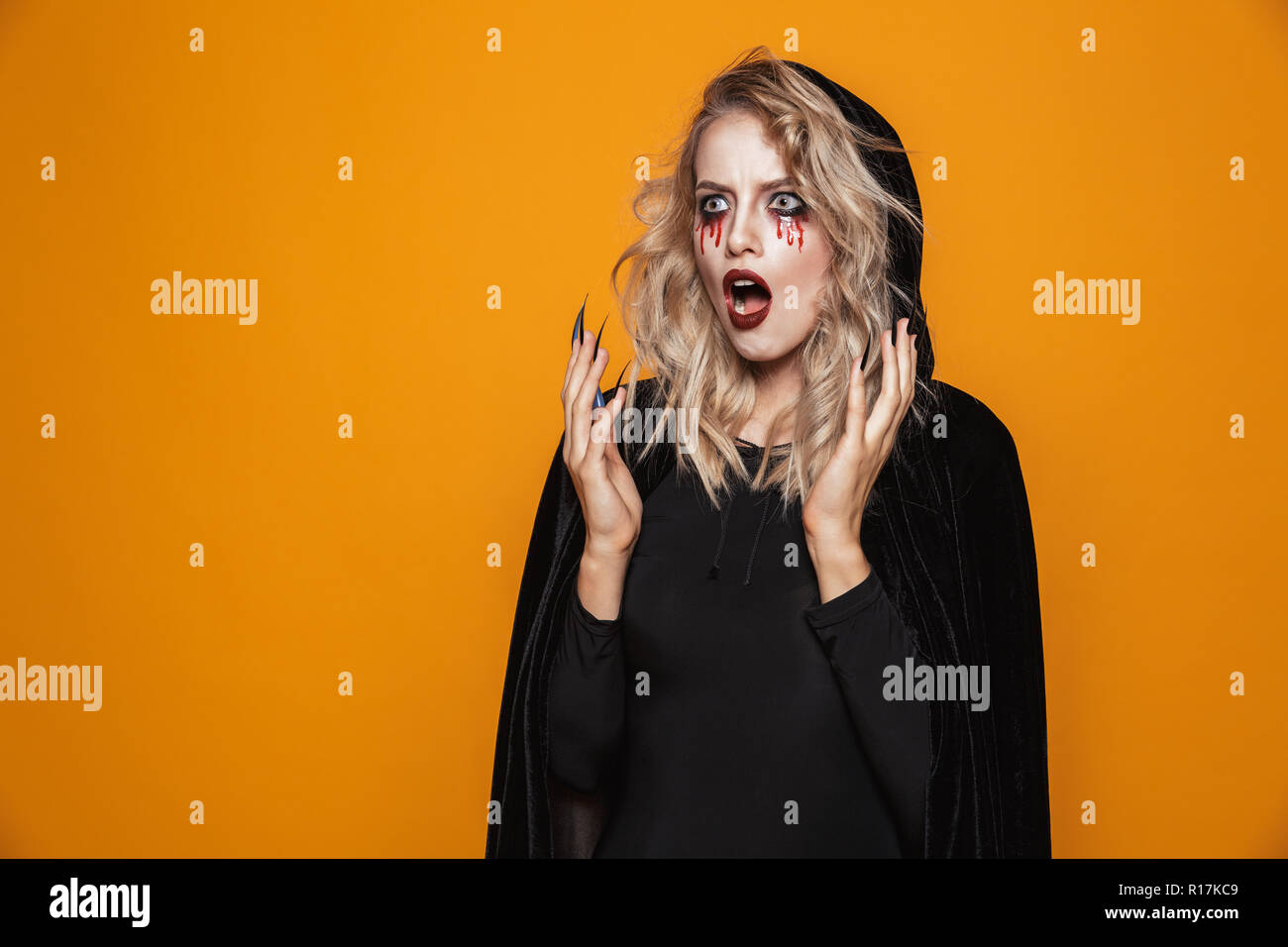 Shocked woman witch with opened mouth and scary makeup looking aside