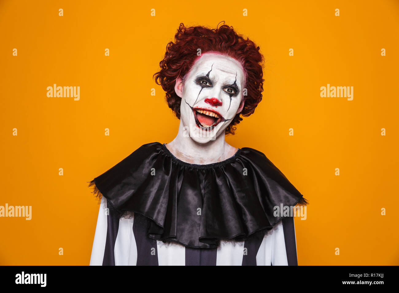 Smiling Man Clown With Scary Make Up Looking Camera And Smiling Isolated Oveer Orange Stock Photo Alamy