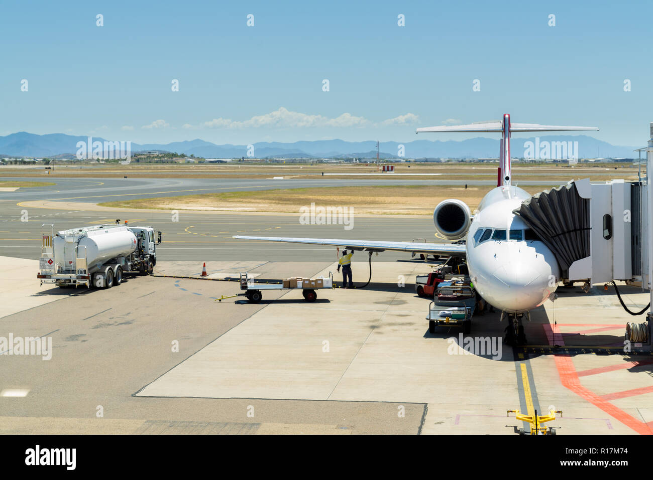 Luggage being loaded and plane being refuelled in preparation for takeoff at Townsville airport, Australia Stock Photo