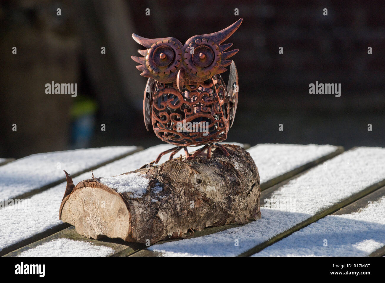 Garden ornament with solar light in the stylised shape of an owl on a garden table with a light snow cover in winter Stock Photo