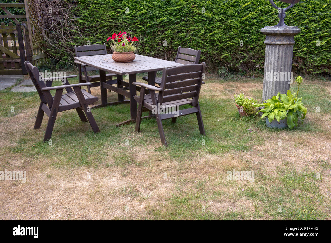 Garden table and chairs on a lawn with dead dry patches during a summer drought, Berkshire, July Stock Photo