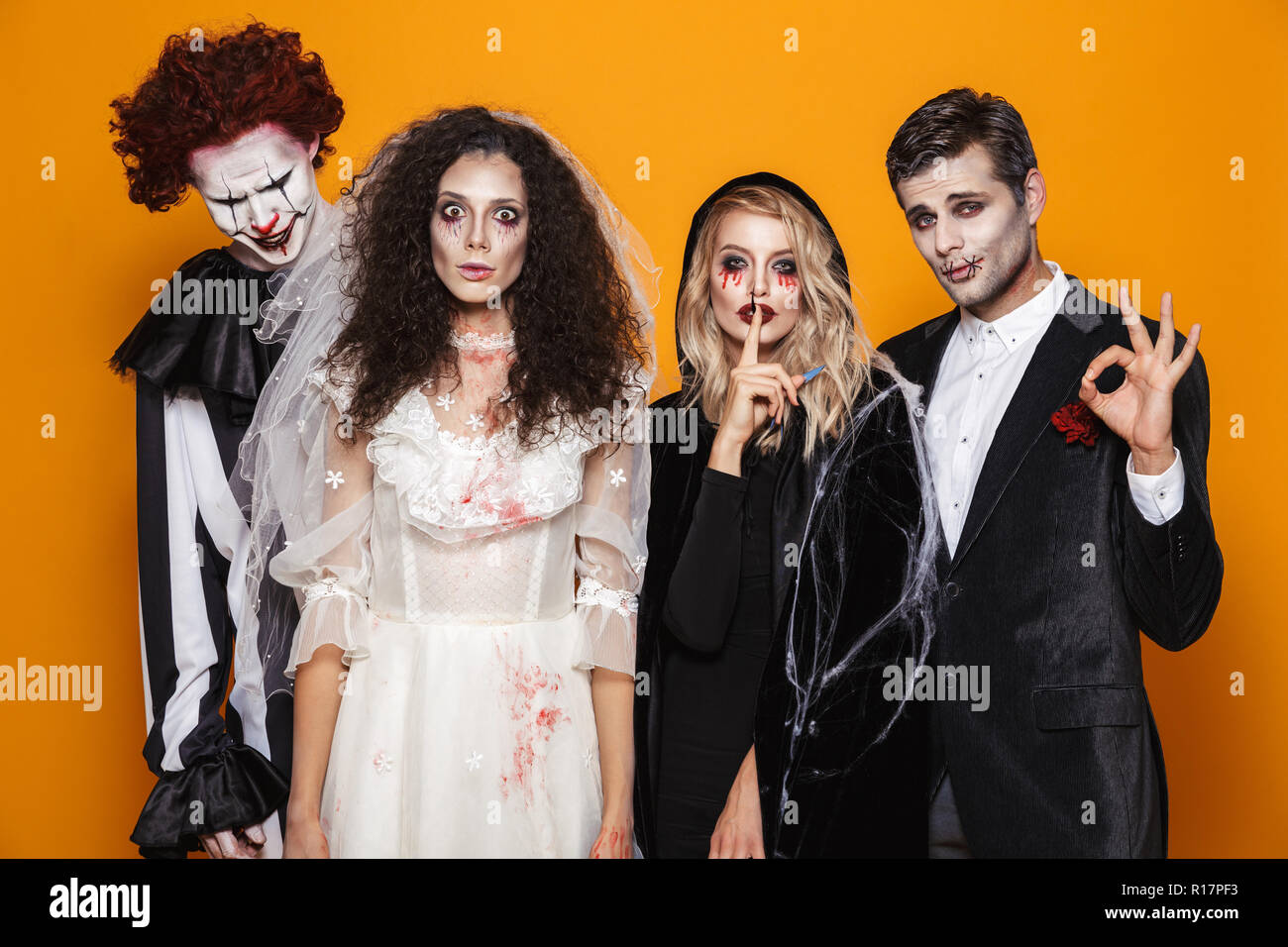 Group of friends dressed in scary costumes celebrating Halloween isolated over yellow background Stock Photo