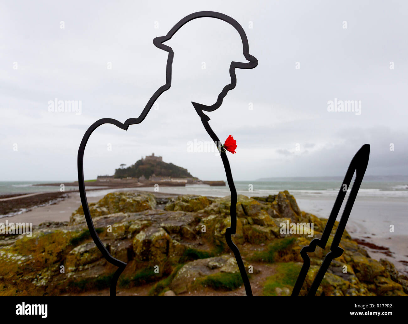 An installation for the Fallen.  A silhouette Tommy figure on Chapel Rock, in front of St Michael's Mount in Marazion, Cornwall, as part of There but  Stock Photo