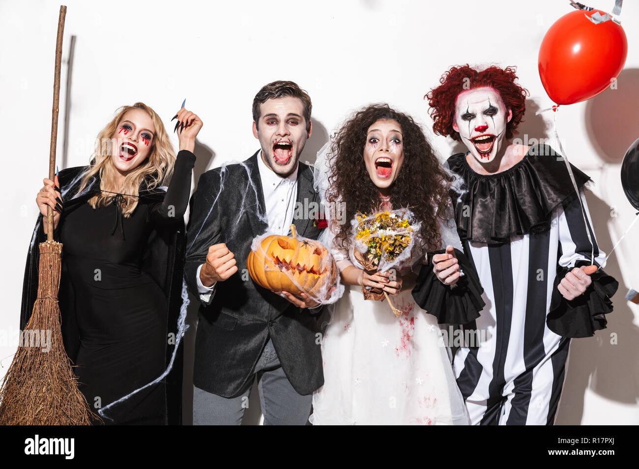 Group of happy friends dressed in scary costumes celebrating Halloween  under confetti rain isolated over white background, holding balloons,  curved pu Stock Photo - Alamy