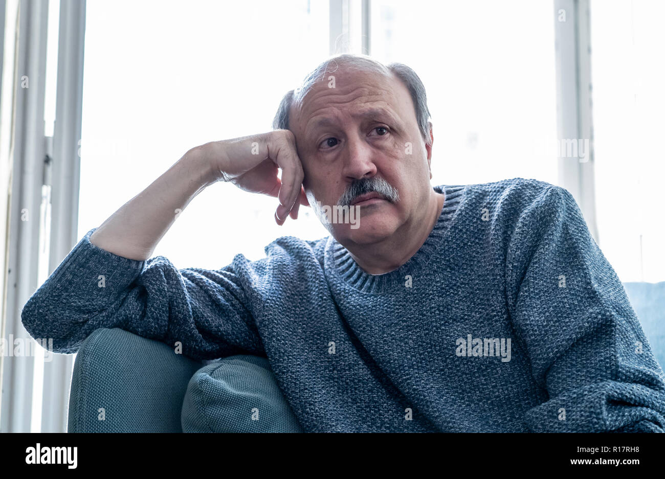 Senior old man feeling desperate sad looking worried depressed thoughtful and lonely on couch at home in Aging Mental health Personal problems and Lif Stock Photo