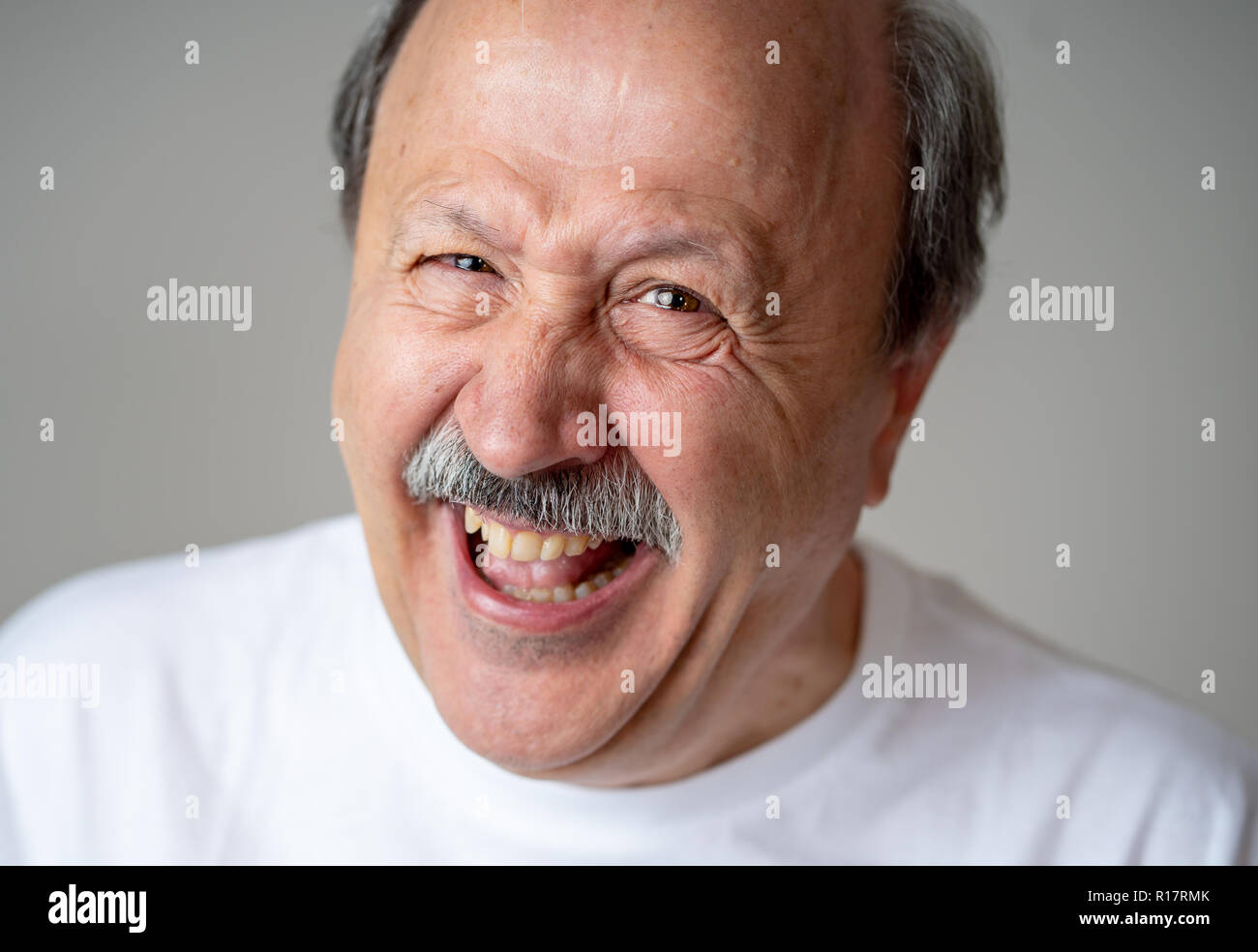 Smiling and laughing 60s year old senior man candid close up portrait in human emotions and facial expressions concept isolated in neutral background. Stock Photo