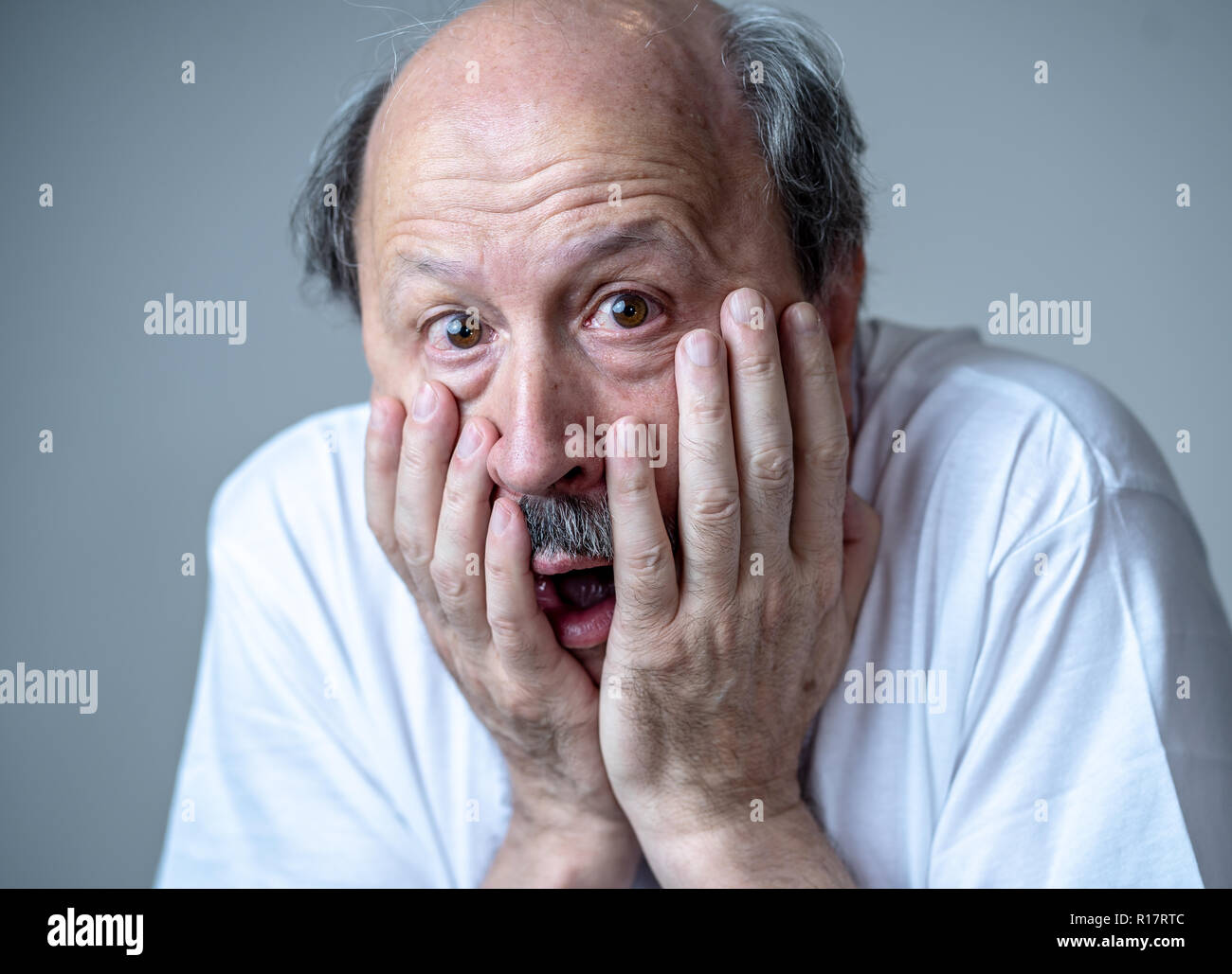 Close up portrait of a scared frightened old man in expression of fear in human emotions and facial expressions isolated in neutral background. Stock Photo