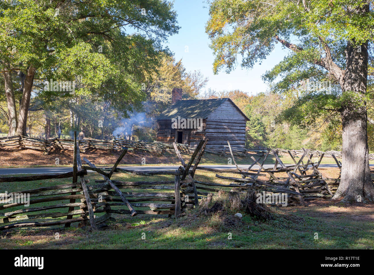 MCCONNELLS, SC (USA) - November 3, 2018:  Smoke rises from a camp fire with rustic log cabin and split-rail fence during a Civil War reenactment. Stock Photo