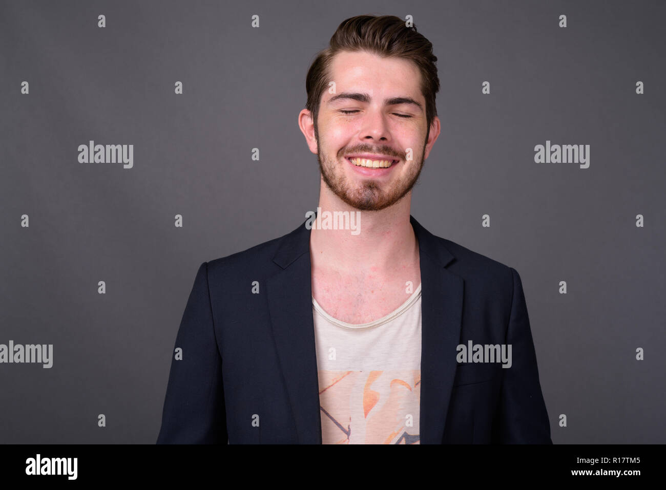 Young handsome bearded businessman against gray background Stock Photo