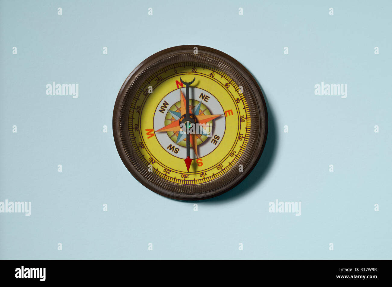 Magnetic compass with yellow face pointing towards south, white background Stock Photo