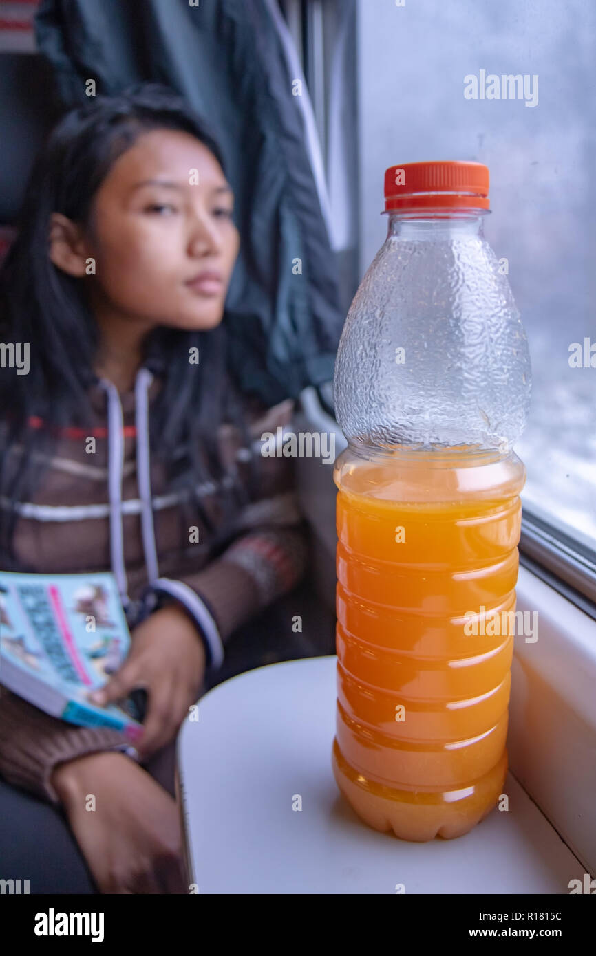 https://c8.alamy.com/comp/R1815C/a-young-woman-riding-by-train-with-traveler-guide-book-and-a-bottle-of-orange-juice-on-the-table-under-window-R1815C.jpg