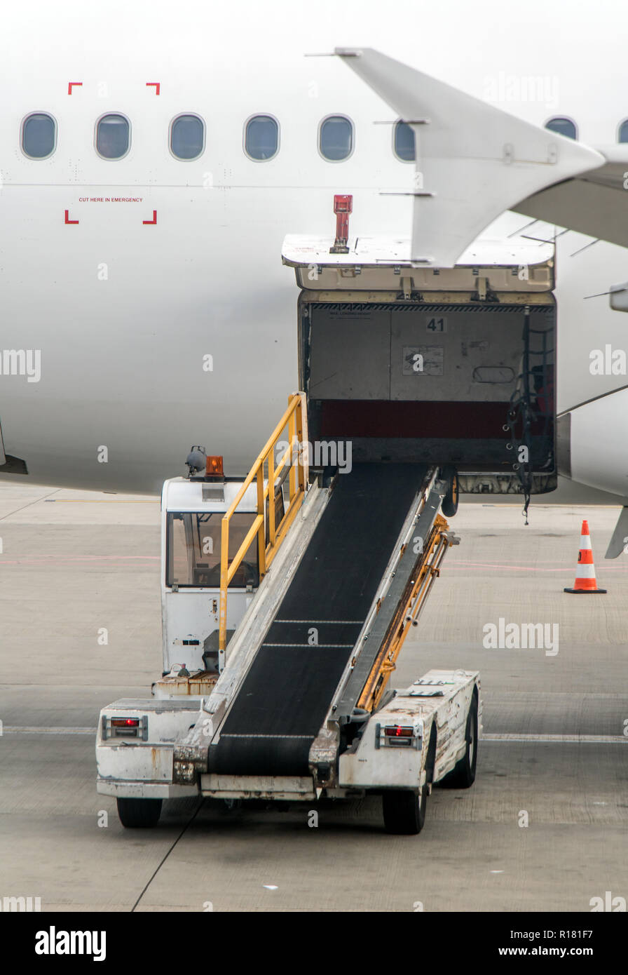 The cargo space of the aircraft is open. The vehicle with conveyor for freight standing beside an empty plane. Stock Photo