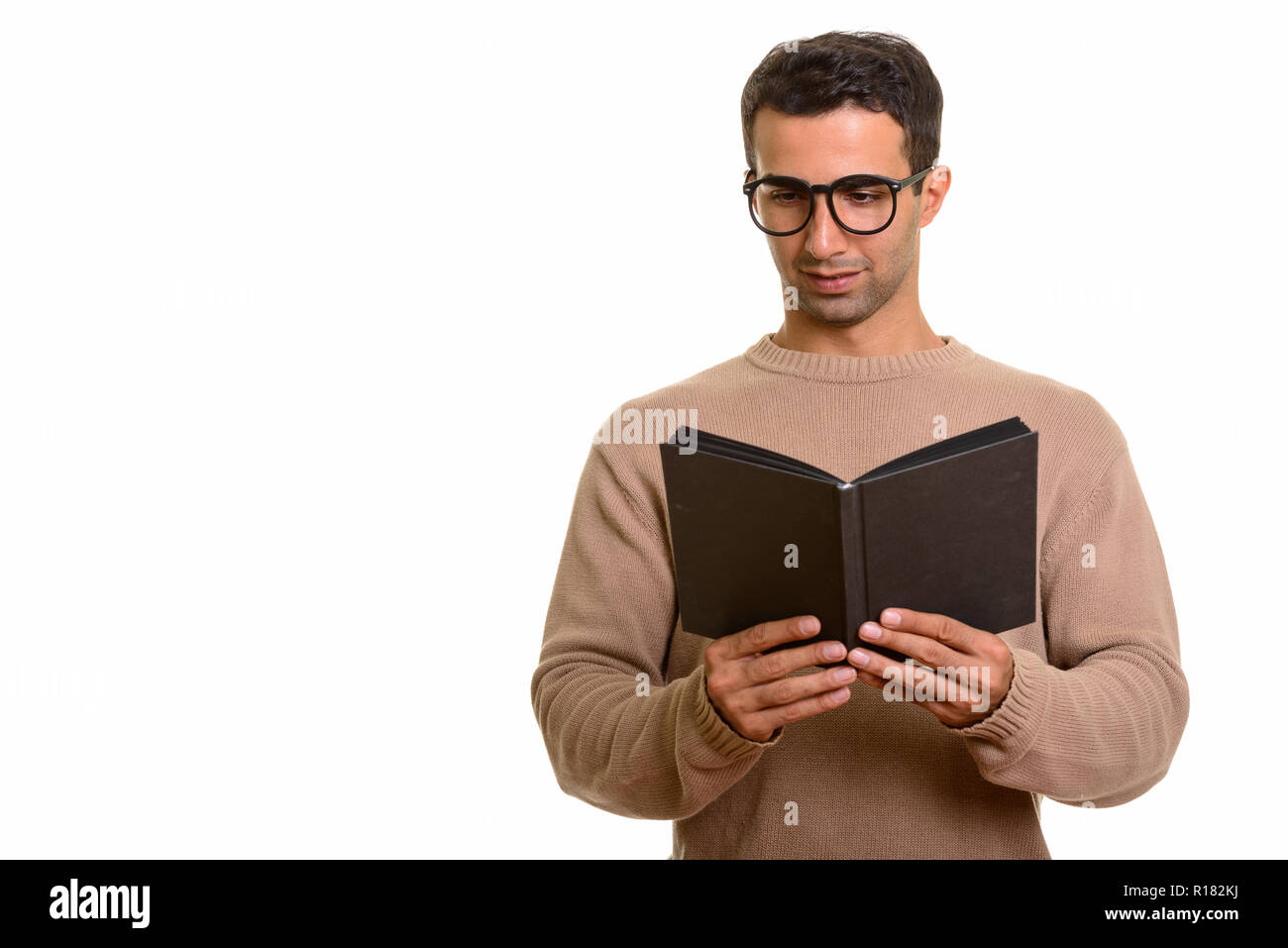 Portrait of young handsome Persian man reading diary or book Stock Photo
