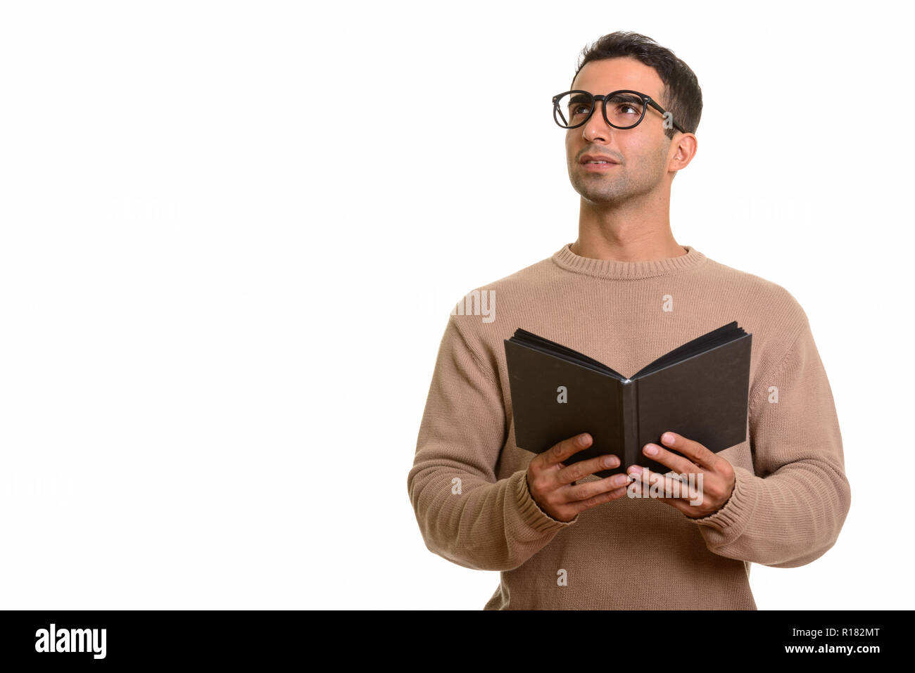 Portrait of young handsome Persian man reading diary or book Stock Photo