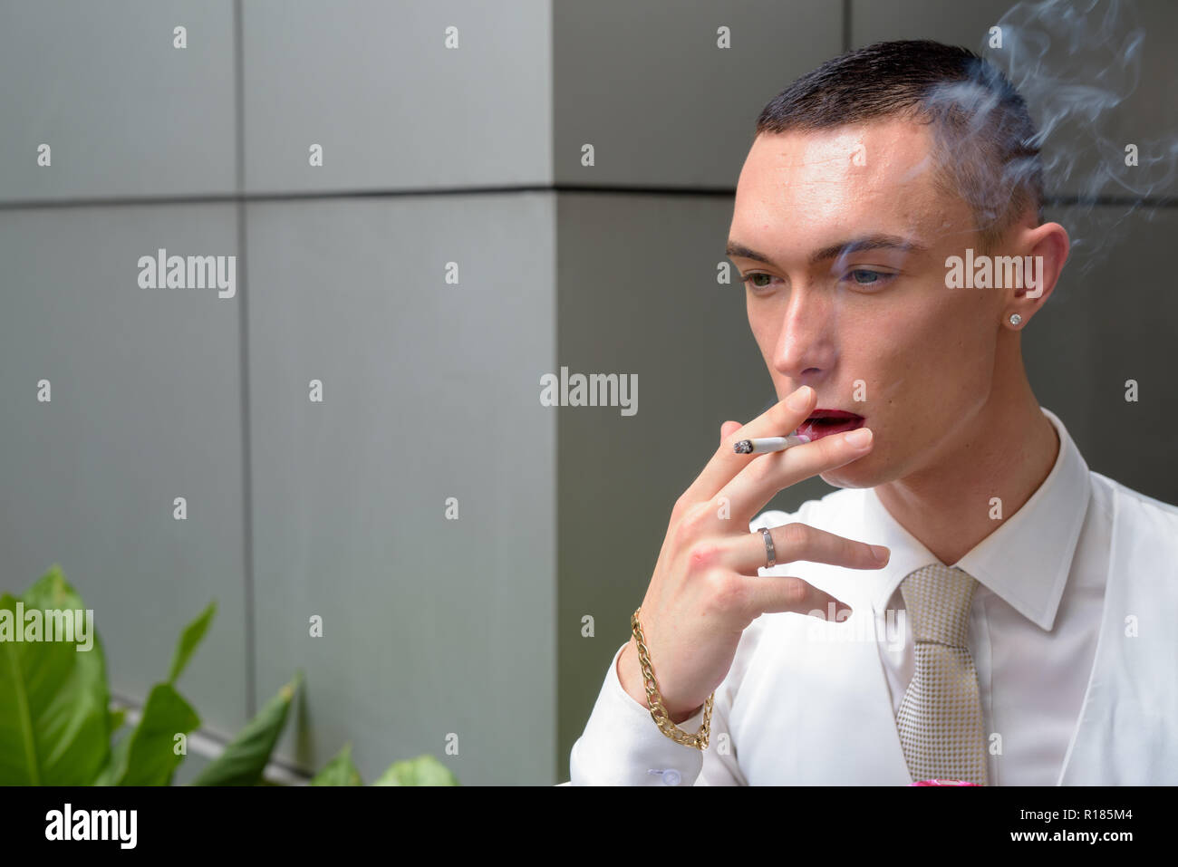 Young androgynous homosexual LGTB businessman smoking cigarette Stock Photo