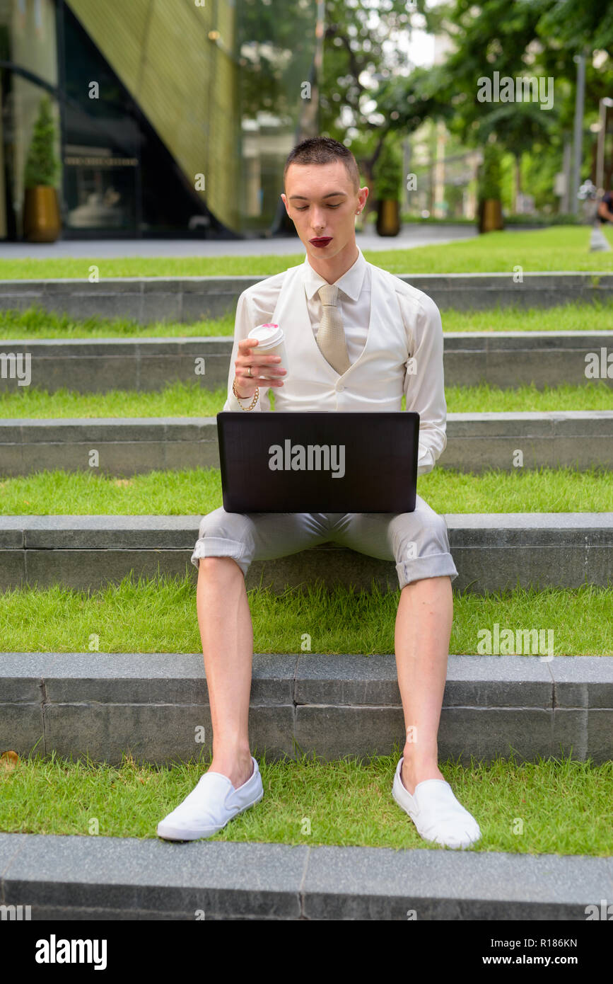 LGTB businessman sitting on stairs while using laptop computer Stock Photo