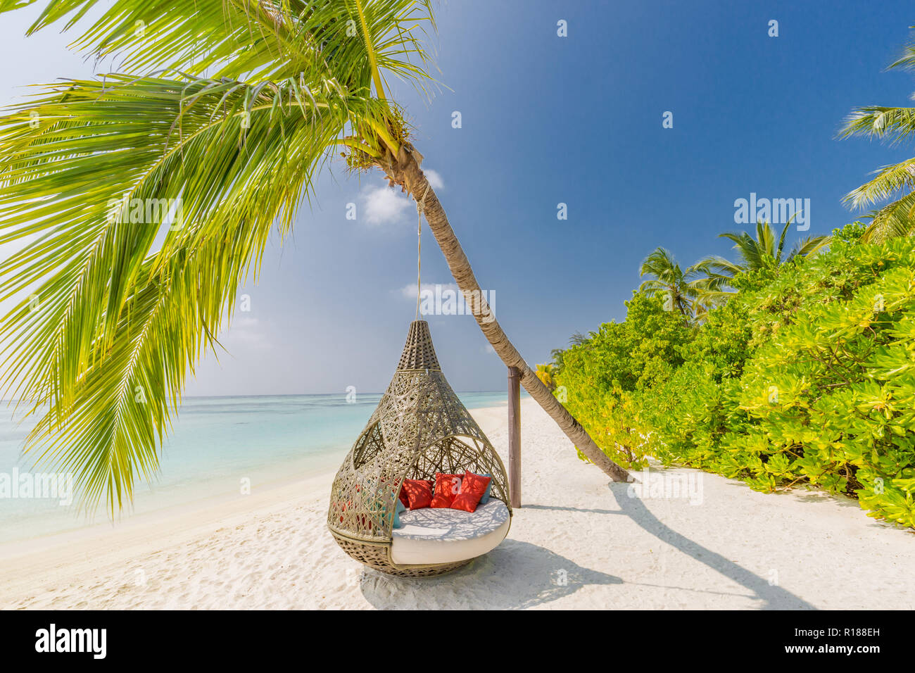 Beautiful tropical Maldives beach under cloudy sky with swings on coconut palm. Luxury vacation Stock Photo