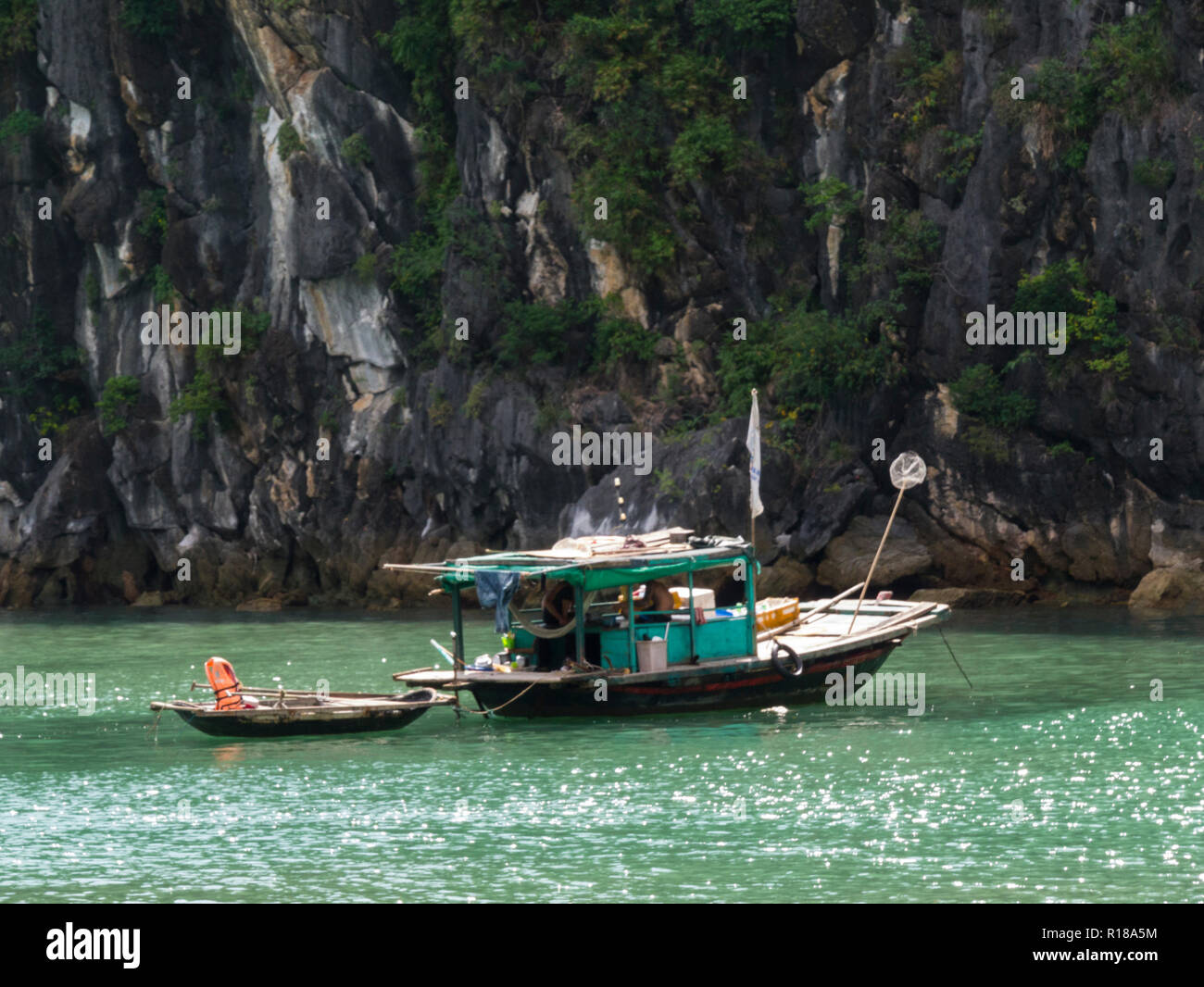 Small fishing boat in Halong Bay South China Sea Vietnam Asia prolific fishing area alongside limestone island peak Stock Photo