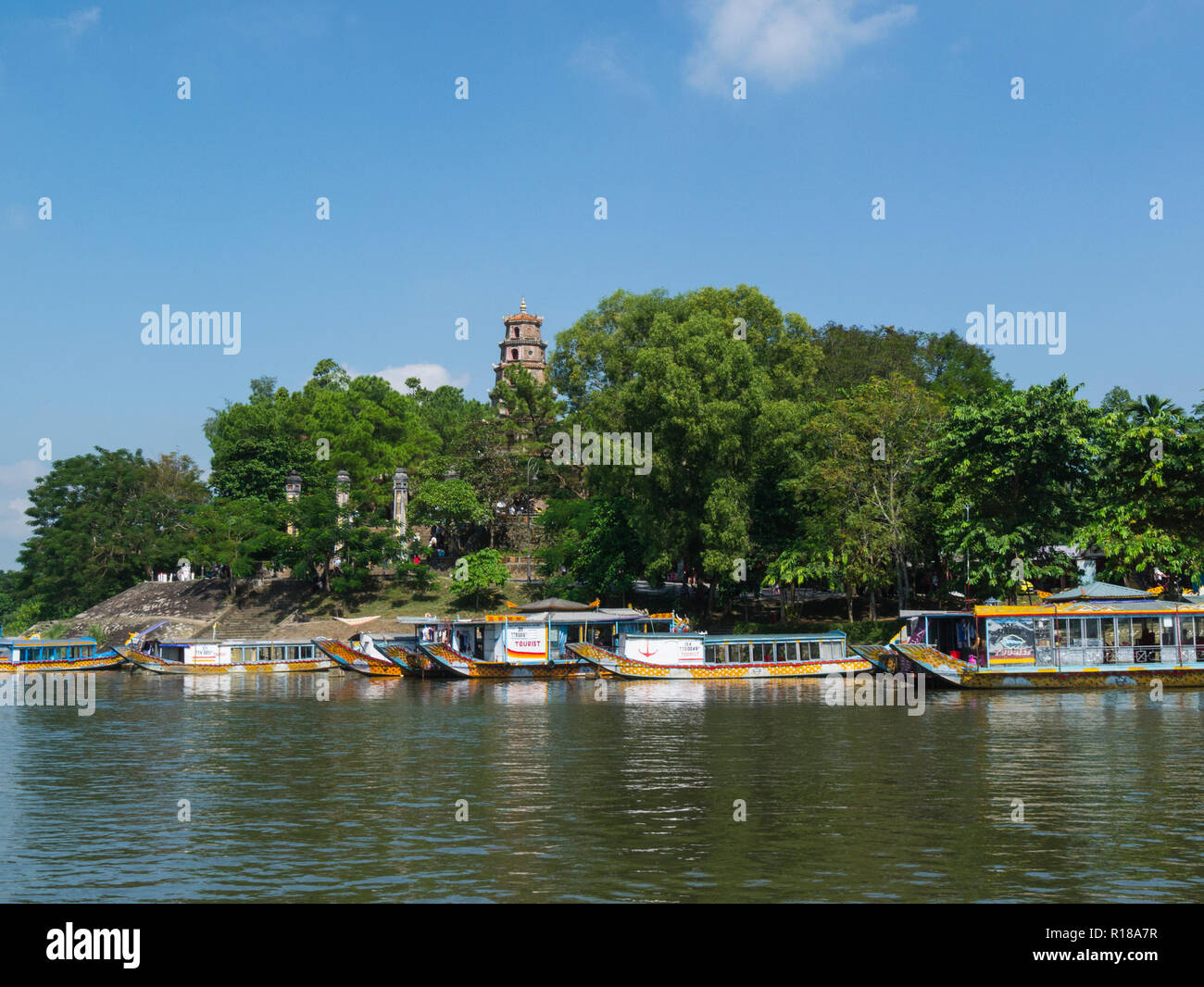 Dragon boats moored front Phuoc Duyen tower in Thien Mue Pagoda Pagoda of the Celestial Lady on Song Huong Perfume River Hue City former Royal Capital Stock Photo