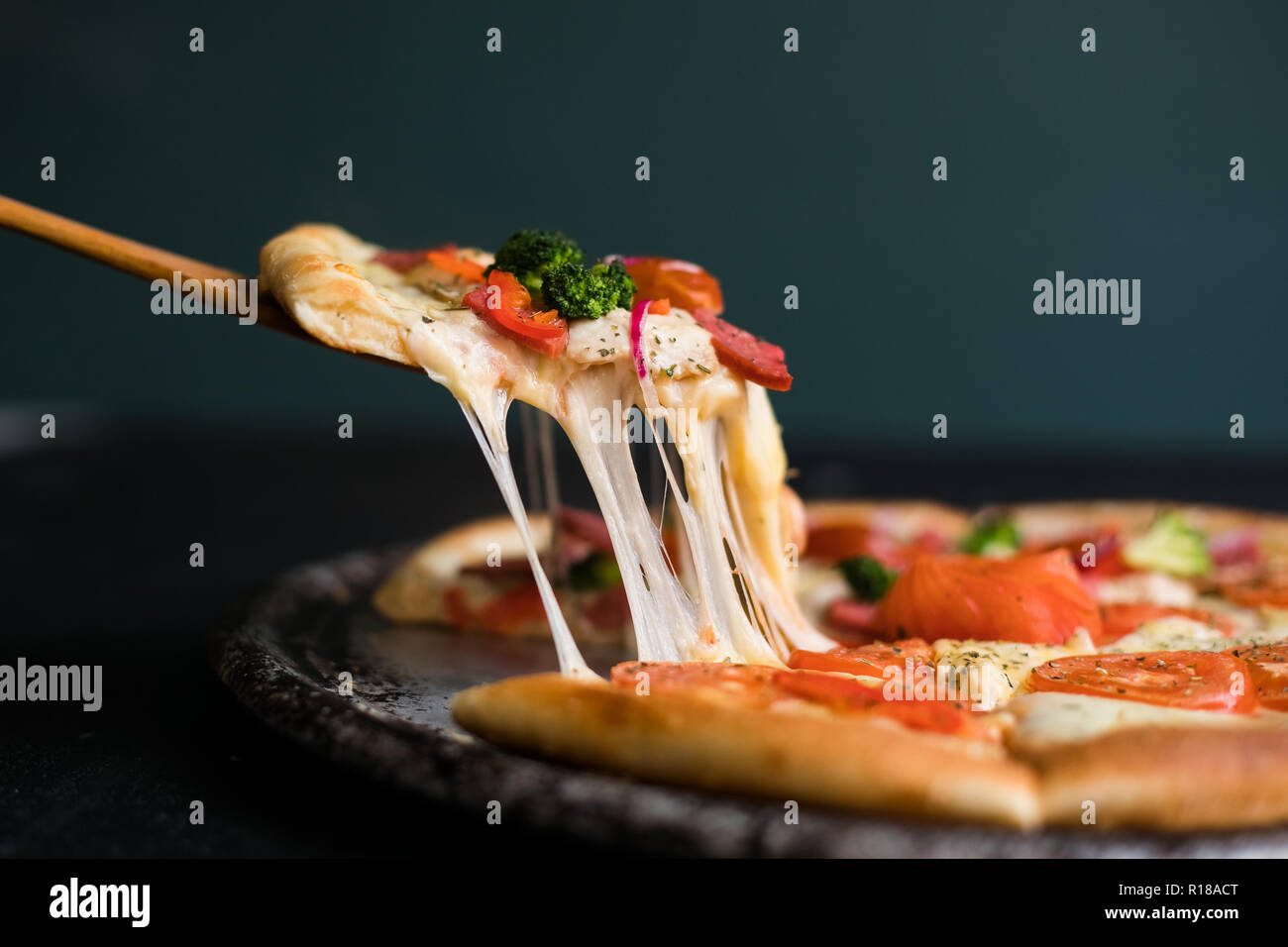 Delicious cheese stringy slice lifted of full supreme pizza baked fresh