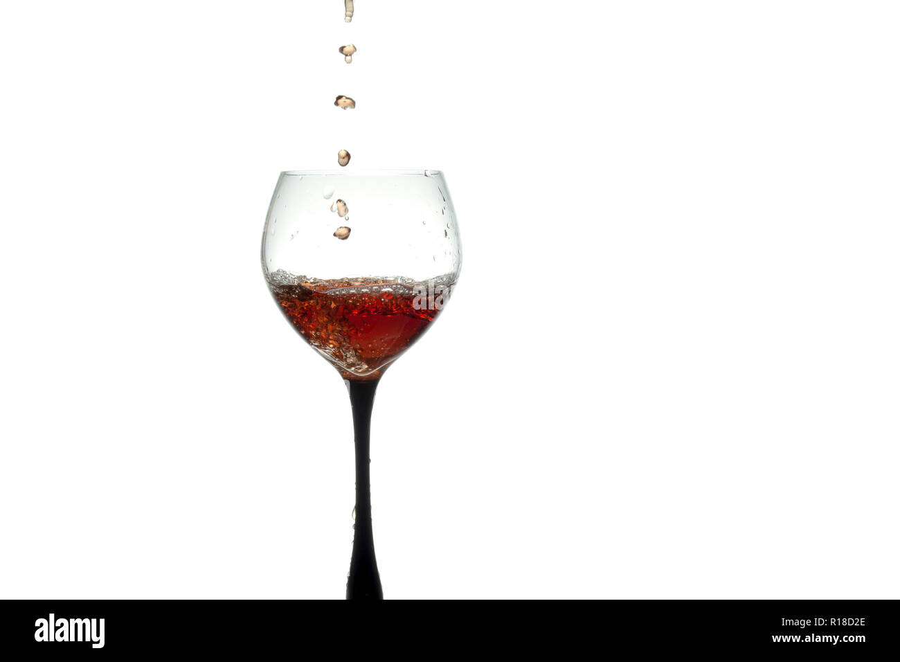 Stream of wine being pouring into a glass closeup, wine splashing in a